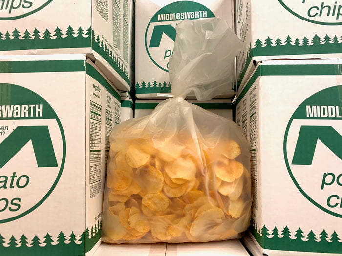 A clear plastic bag filled with BBQ flavored Middleswarth potato chips, placed inside a green and white cardboard box.