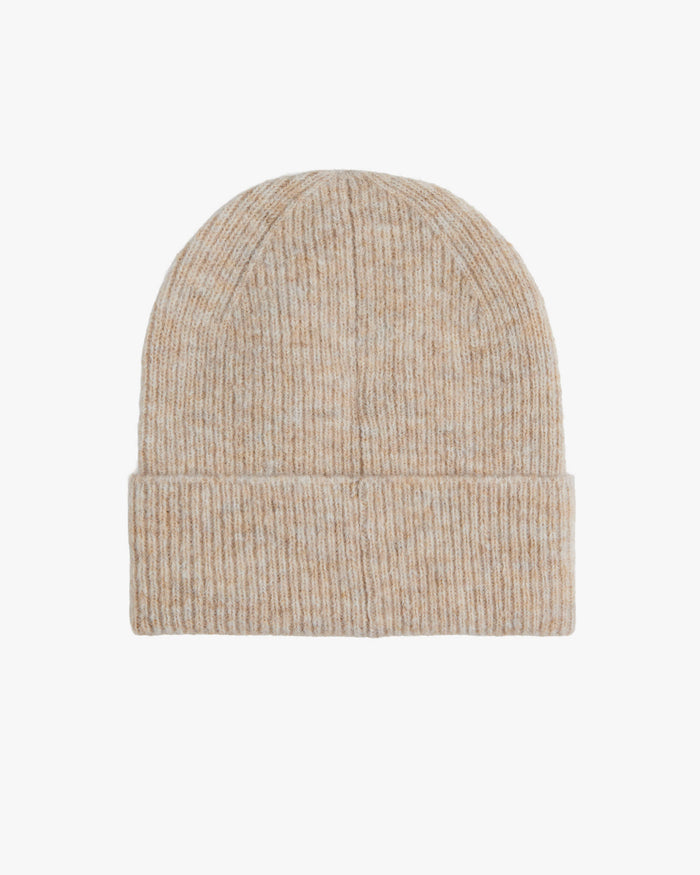 A front view of The Hairy Beanie in light beige, laid flat on a white background. The image highlights the ribbed knit texture and the folded brim.