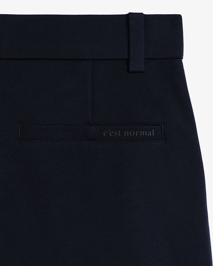 The Proper Pant Relaxed Straight Fit in navy — close-up of the back welt pocket with C'est normal logo