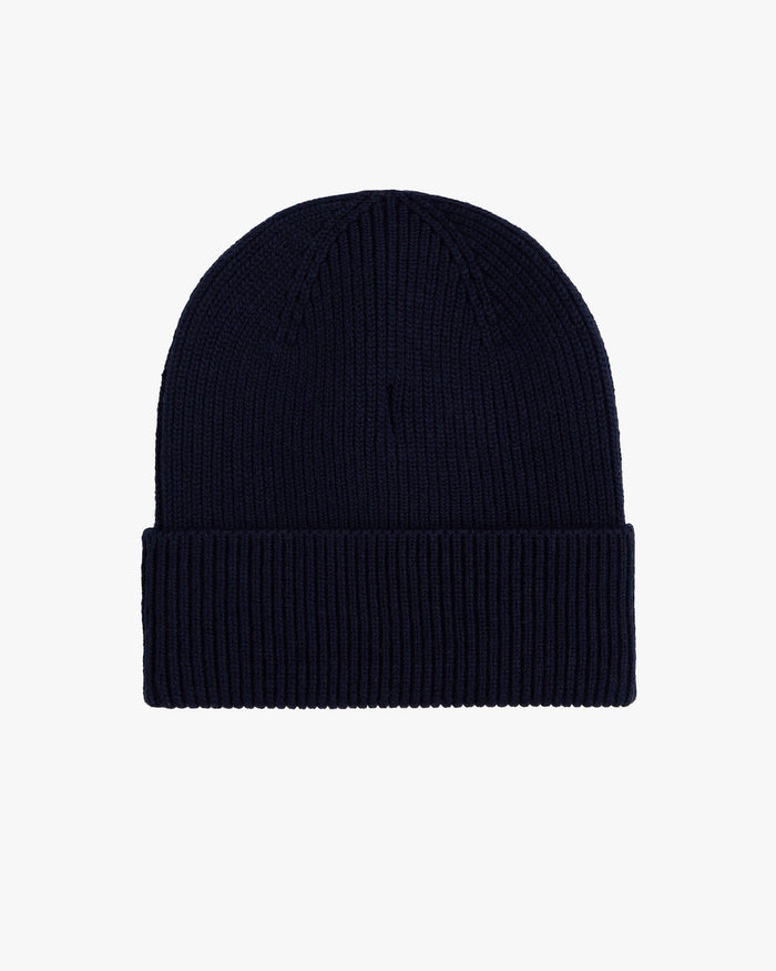 A back view of The Ribbed Beanie in navy, laid flat on a white background, highlighting its classic ribbed knit texture and folded brim.