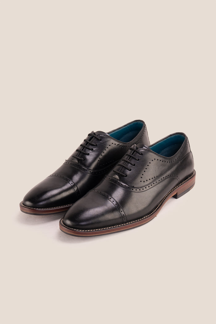 Premium men's black leather oxford shoes by Oswin Hyde London, featuring a cap toe with decorative perforations, closed lacing, contrast welt stitching, and a cushioned teal interior.