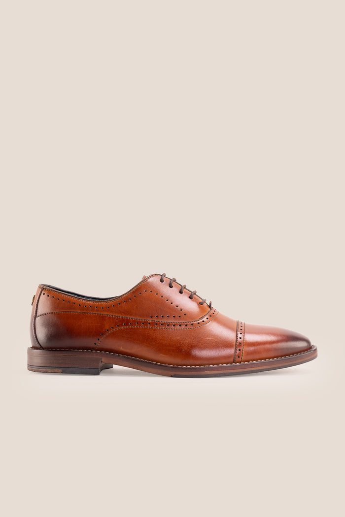 Premium men's tan leather oxford shoes by Oswin Hyde London, featuring a cap toe with decorative perforations, closed lacing, contrast welt stitching, and a cushioned teal interior.