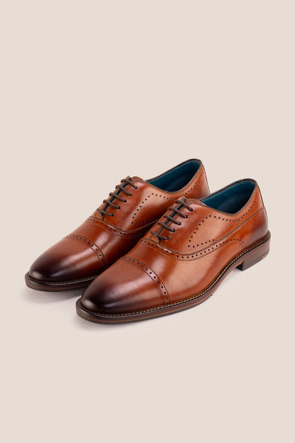 Premium men's tan leather oxford shoes by Oswin Hyde London, featuring a cap toe with decorative perforations, closed lacing, contrast welt stitching, and a cushioned teal interior.