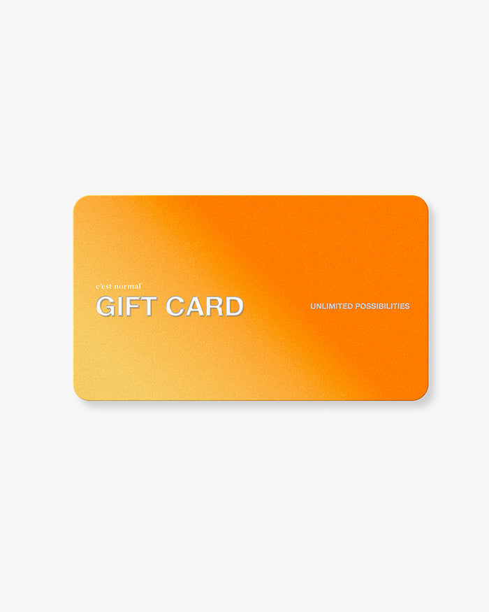 A front view of the c'est normal Gift Card, laid flat against a white background. The orange and yellow gradient card features the brand logo, 'GIFT CARD' in large white letters, and the text 'UNLIMITED POSSIBILITIES'.