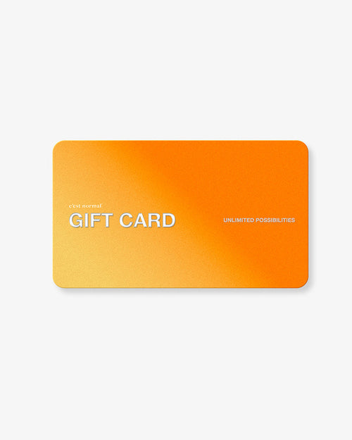 A front view of the c'est normal Gift Card, laid flat against a white background. The orange and yellow gradient card features the brand logo, 'GIFT CARD' in large white letters, and the text 'UNLIMITED POSSIBILITIES'.