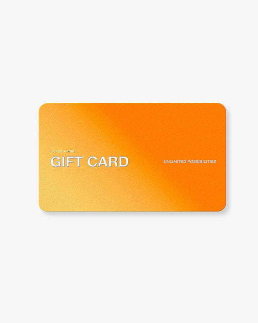 A front view of the c'est normal Gift Card, laid flat against a white background. The orange and yellow gradient card features the brand logo, 'GIFT CARD' in large white letters, and the text 'UNLIMITED POSSIBILITIES'.