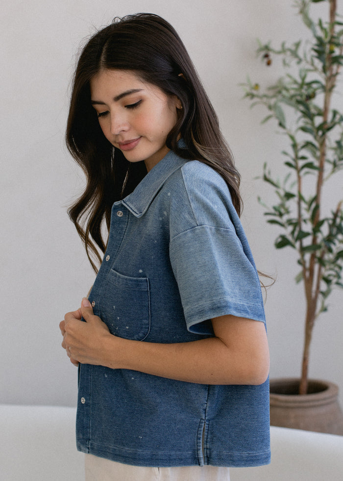 details of woman wearing cropped indigo short sleeve button down in vintage wash