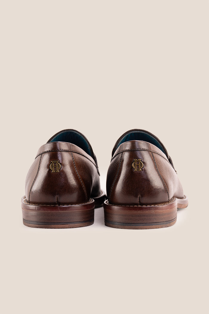 Premium brown leather tassel loafers for men featuring a textured finish, burnished moc-toe details, decorative leather tassels, and a cushioned teal interior.