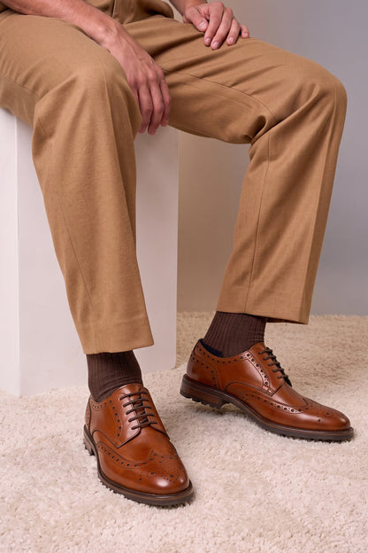 Model wearing George Tan leather shoes for men. Featuring a five-eyelet wing cap brogue design, these shoes offer timeless style and comfort