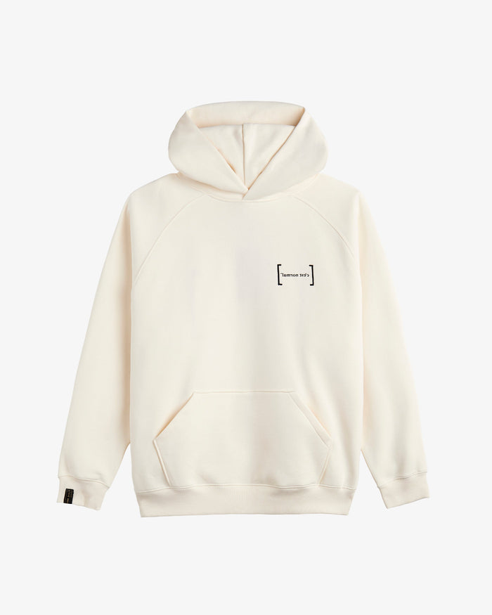 A front view of Le Hoodie in cream, laid flat on a white background. The image highlights the oversized fit, kangaroo front pocket, the FRC mirror logo on the chest, and the signature c'est normal cuff tag on the sleeve.