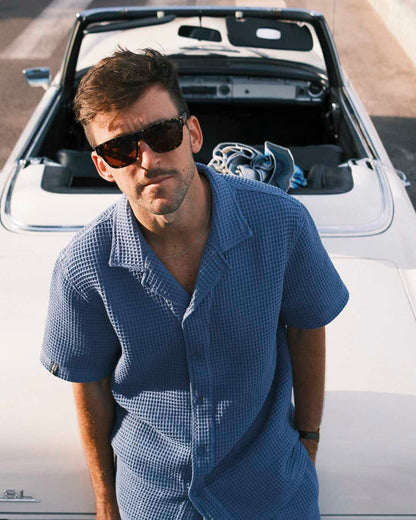 Le Waffle Resort Shirt in azure — worn leaning against a white vintage convertible