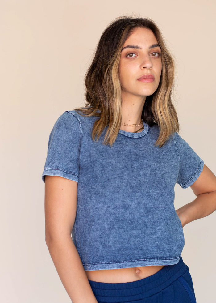 Woman wearing a blue crop tee against a beige background
