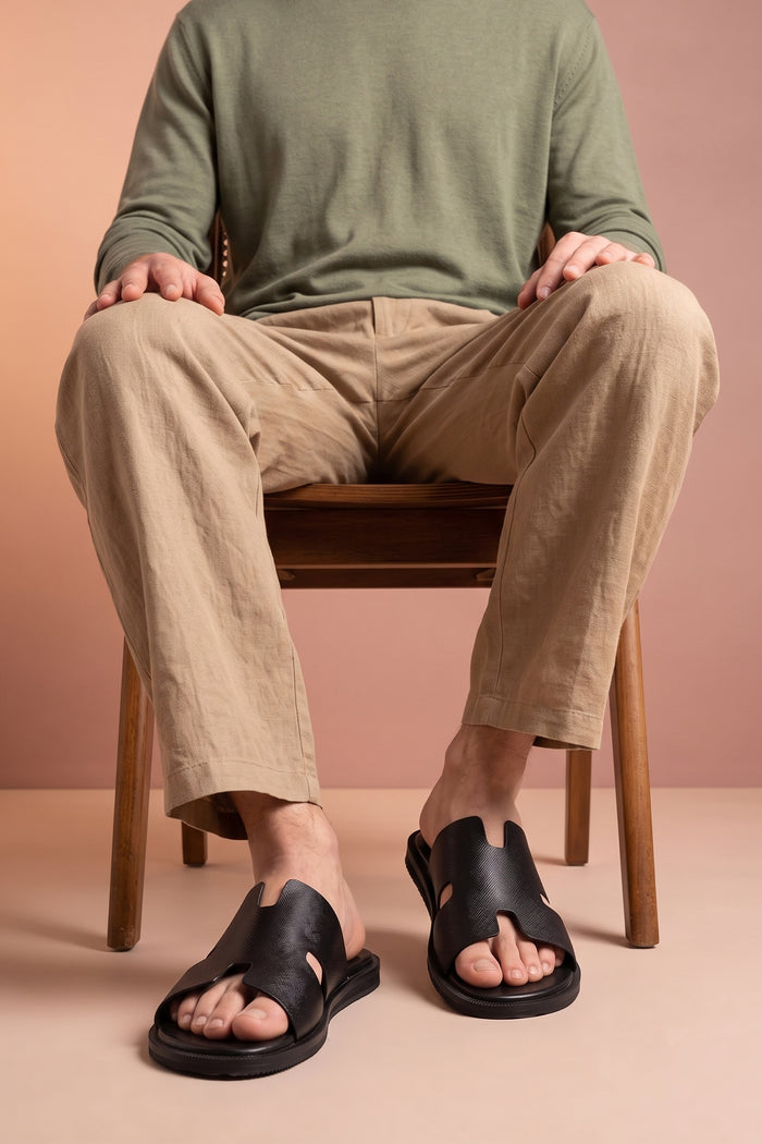 Model wearing Men’s Phoenix Black sandals in premium Saffiano leather featuring the signature hyde strap H-frame design.