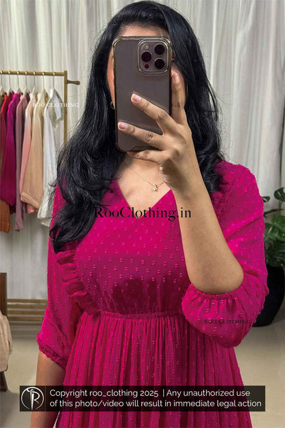 Woman wearing fuchsia pink chiffon midi dress with v-neckline, balloon sleeves, empire waist, and tiered hem – Roo Clothing