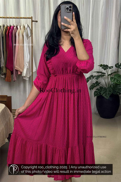 Woman wearing fuchsia pink chiffon midi dress with v-neckline, balloon sleeves, empire waist, and tiered hem – Roo Clothing