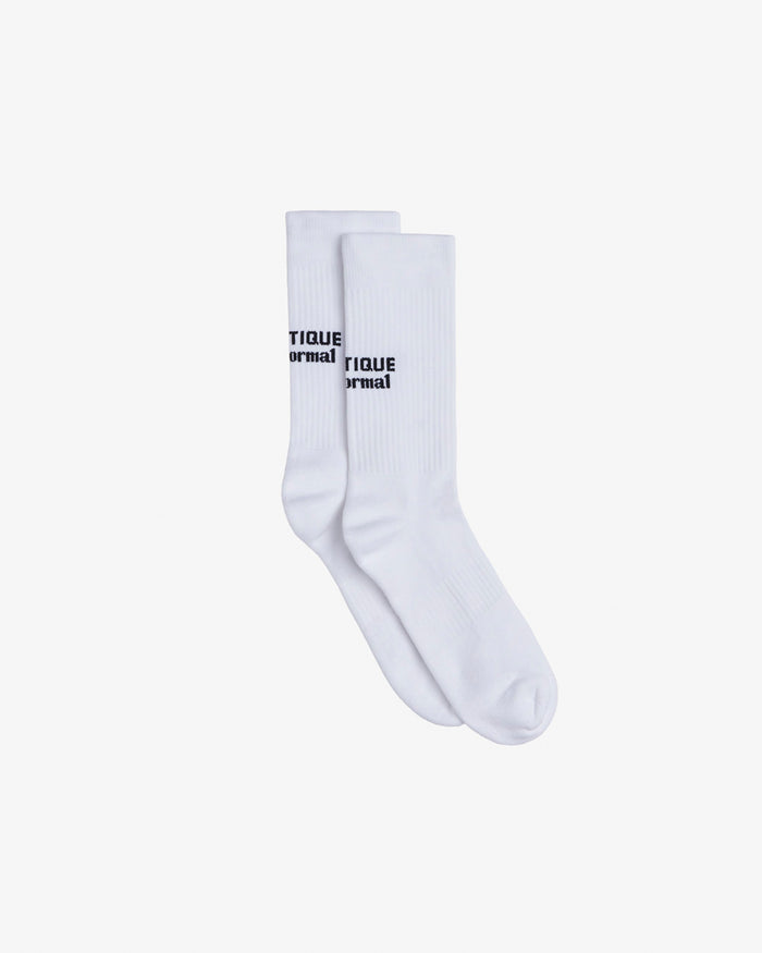 A pair of The Athlétique Socks in white, laid flat on a white background. The image highlights the mid-calf design with the c'est normal logo in black contrast stitching.