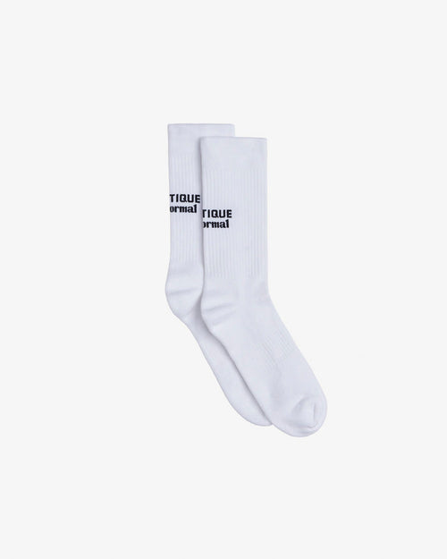 A pair of The Athlétique Socks in white, laid flat on a white background. The image highlights the mid-calf design with the c'est normal logo in black contrast stitching.