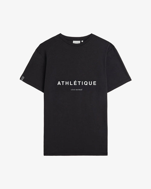A front view of The Athlétique Tee in black, laid flat on a white background. The image highlights the white Athlétique text and c'est normal logo on the chest, along with a small cuff tag on the right sleeve.