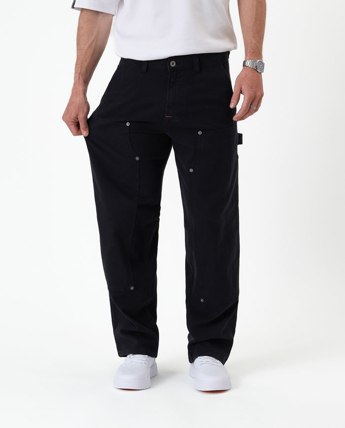 The Carpenter Pant in black — fabric being pulled to show the flexible stretch material