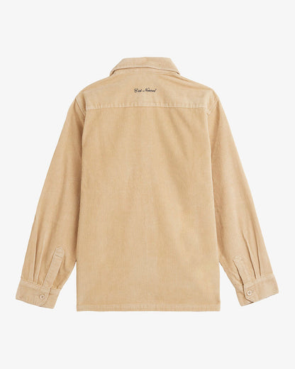 A back view of The CÔTELÉ Corduroy Overshirt in Irish Cream, laid flat on a white background. The image highlights the corduroy texture, buttoned cuffs, and the embroidered c'est normal logo at the back of the neck.