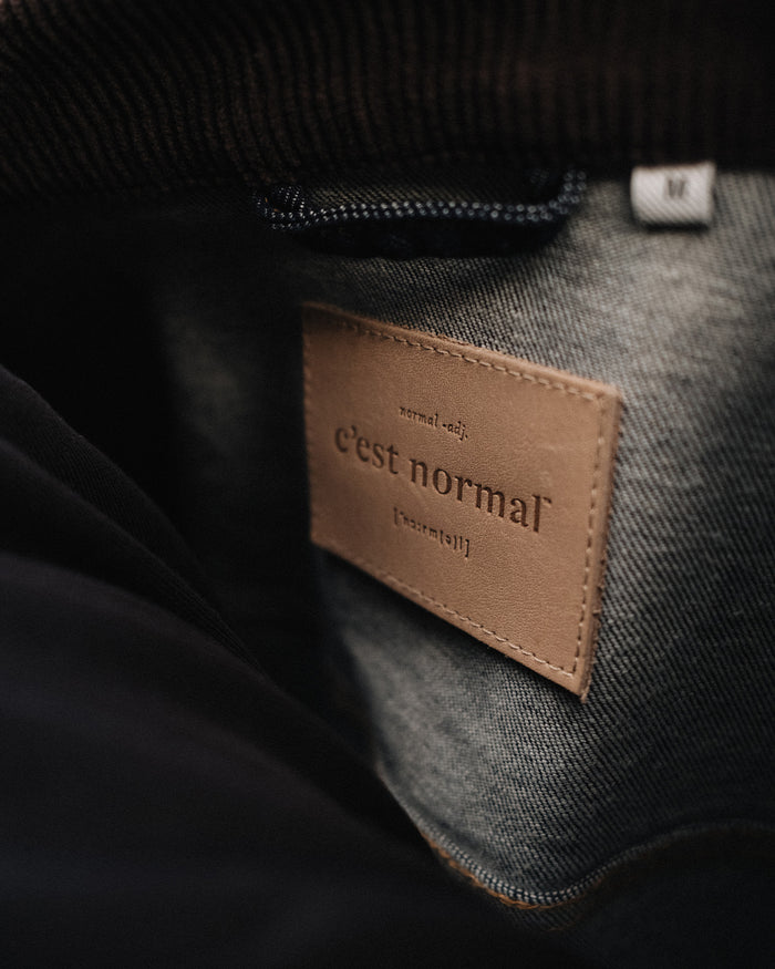 The Denim Jacket in rinse — close-up of the C'est normal neck label