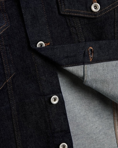 The Denim Jacket in rinse blue — close-up of silver shank buttons engraved with C'est normal