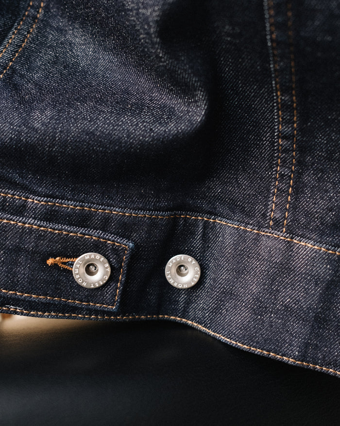 The Denim Jacket in rinse wash — close-up of the adjustable waist strap and silver buttons