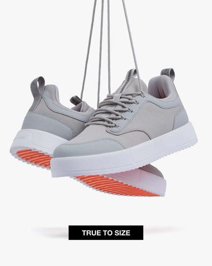 Two The Dynamic Waterproof Sneaker 2.0 Low in Grey/White Waterproof suspended by their laces against a white background. The image highlights the grey waterproof upper, white ultra lightweight EVA midsole, and original orange EVA rubber grid sole. A "TRUE TO SIZE" banner is visible at the bottom.