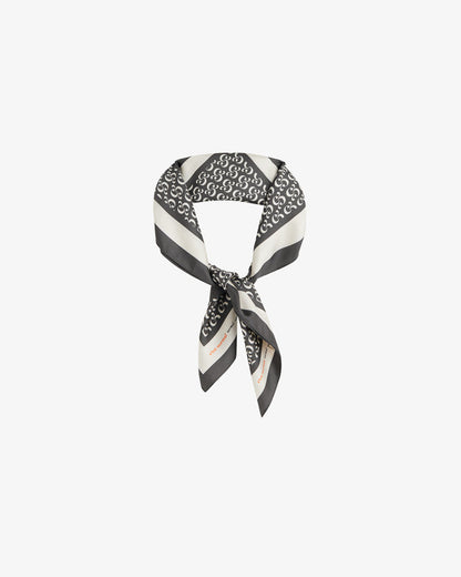 The Fall Bandana tied in a knot, displayed against a white background. The image highlights the signature black and cream repeating monogram print, along with a contrast border featuring the c'est normal wordmark.