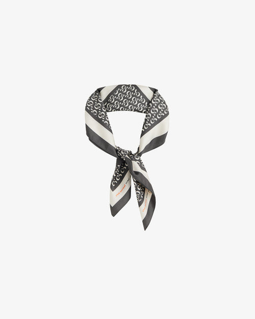 The Fall Bandana tied in a knot, displayed against a white background. The image highlights the signature black and cream repeating monogram print, along with a contrast border featuring the c'est normal wordmark.