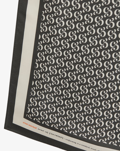 A detailed close-up of The Fall Bandana, showcasing the repeating black and cream monogram print. The image highlights the crisp contrast border with the c'est normal wordmark and definition detail.