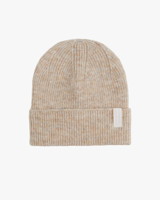 A front view of The Hairy Beanie in light beige, laid flat on a white background. The image highlights the soft knitted texture, the folded brim, and the white c'est normal logo on the brim tag.