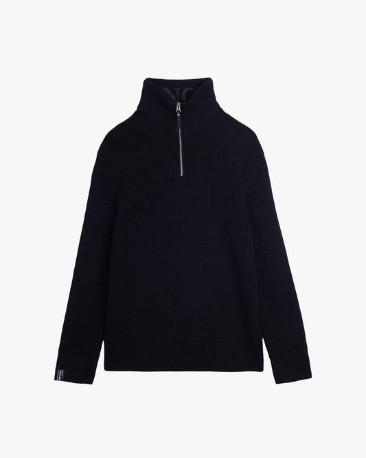 A front view of The Halfzip Sweater in black, laid flat on a white background. The image highlights the standing collar with a metal zipper, the structured knit material, and the c'est normal cuff tag on the right sleeve.