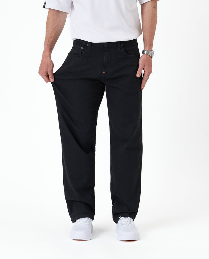 The Jeans Relaxed Straight Fit in jet black — demonstrating the stretch fabric at the thigh