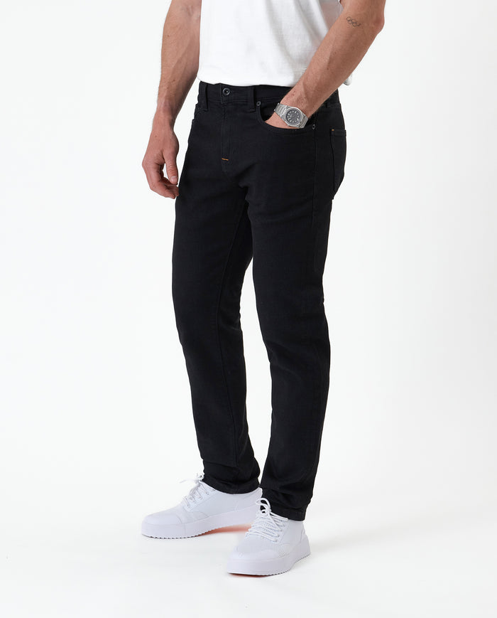 The Jeans Slim Fit in Jet Black — front view worn with white sneakers