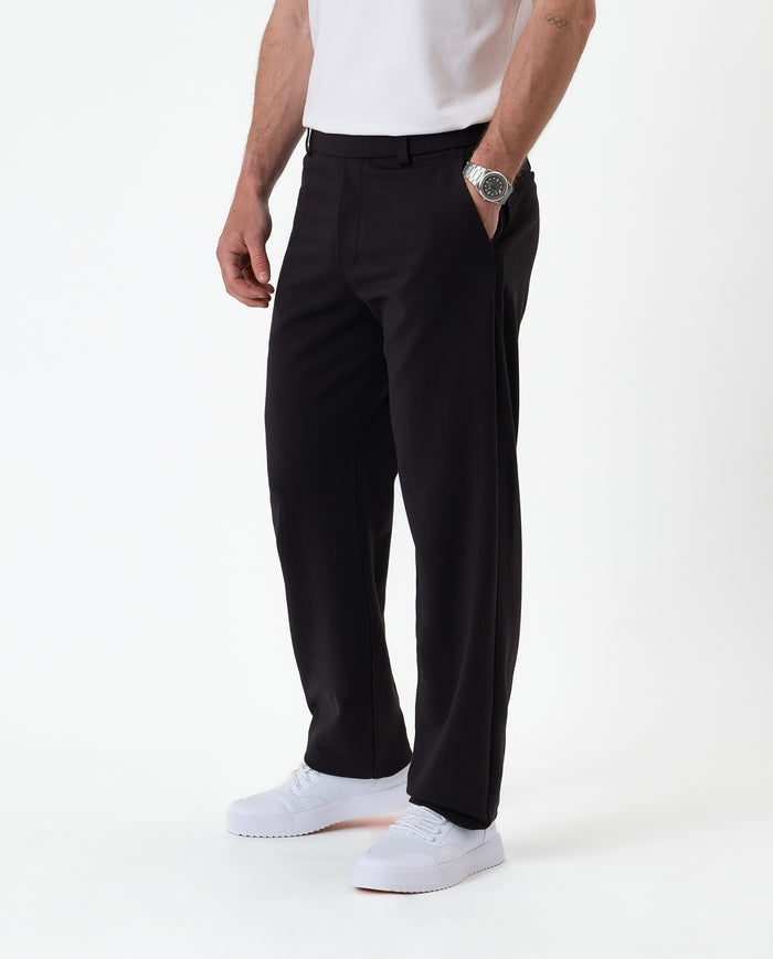 The Proper Pant Relaxed Straight Fit in black — side view styled with white sneakers
