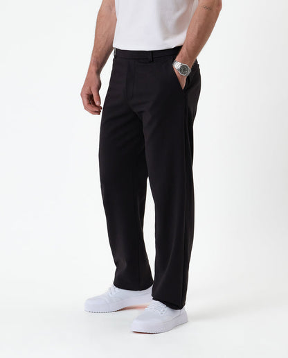 The Proper Pant Relaxed Straight Fit in black — side view styled with white sneakers