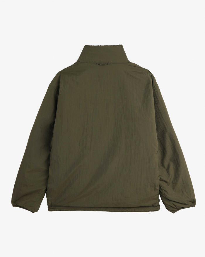 A back view of The Reversible Pile Jacket in forest green, laid flat on a white background. The image highlights the smooth tech side of the jacket and the high collar.