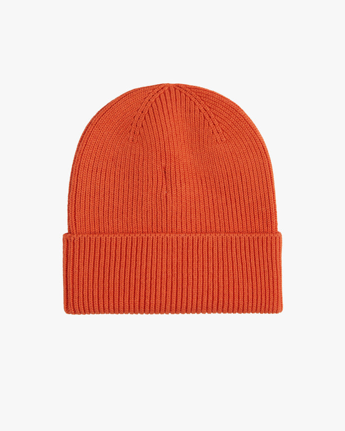 The Ribbed Beanie in orange, laid flat on a white background, highlighting its classic ribbed knit texture and folded brim.