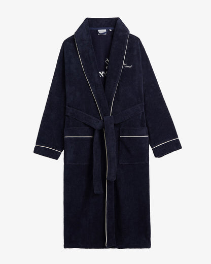 A front view of The Robe in navy, laid flat on a white background. The image highlights the tied belt, two front pockets, white piping, and the embroidered c'est normal logo on the chest.