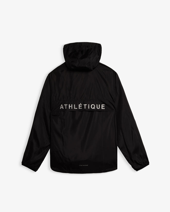 A back view of The Running Jacket in black, laid flat on a white background. The image highlights the hood, the reflective "ATHLÉTIQUE" print across the back ventilation panel, and the small c'est normal logo near the hem.