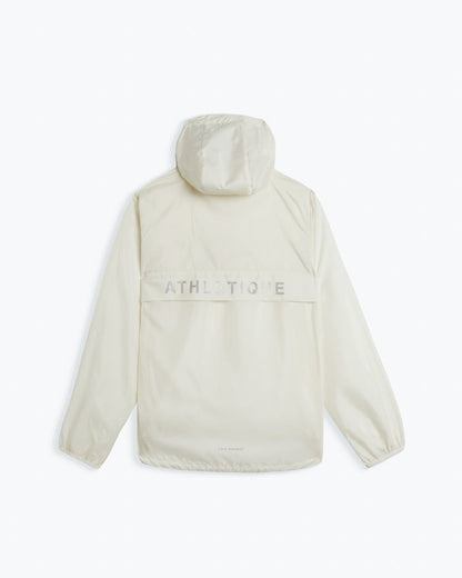 A back view of The Running Jacket in cream, laid flat on a white background. The image highlights the hood, the back ventilation panel with reflective ATHLETIQUE branding, and the c'est normal logo at the bottom.