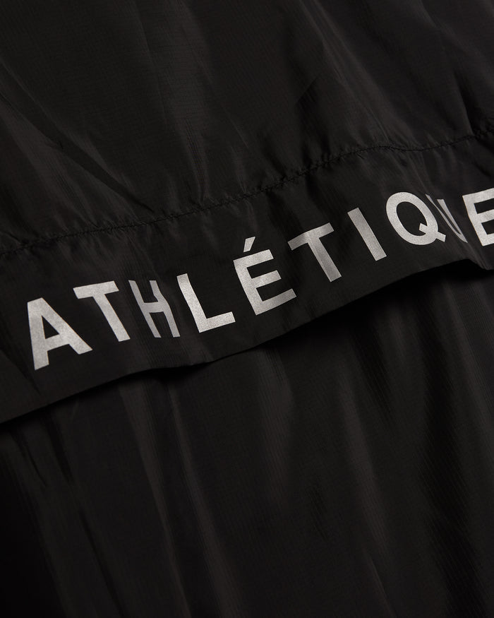A close-up shot of The Running Jacket in black, highlighting the reflective ATHLÉTIQUE branding across the back ventilation panel.