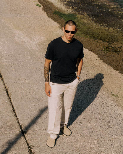 The Sanremo Linen Tee in anthracite grey — worn with cream trousers and sunglasses outdoors