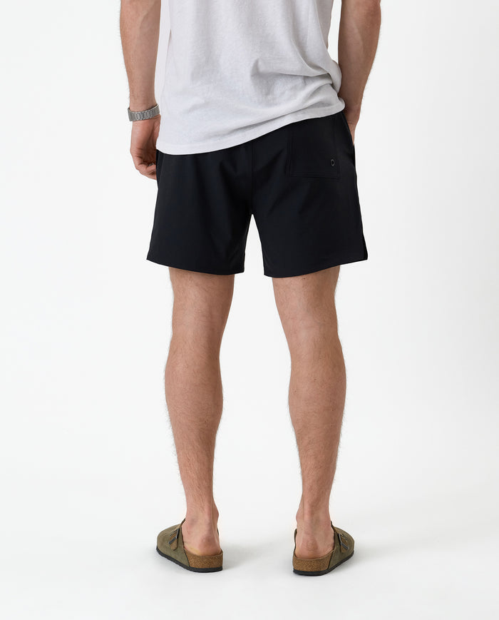 The Shorts in black — back view worn with a white t-shirt and olive sandals