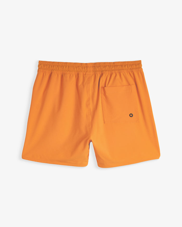 A back view of The Shorts in orange peel, laid flat on a white background. The image highlights the elasticated waistband and a single back pocket with a small eyelet detail.