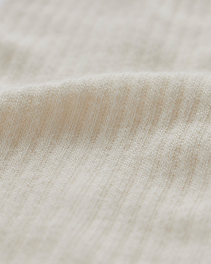 A close-up shot of the knitted fabric of The Sock in cream, highlighting its soft, ribbed texture.