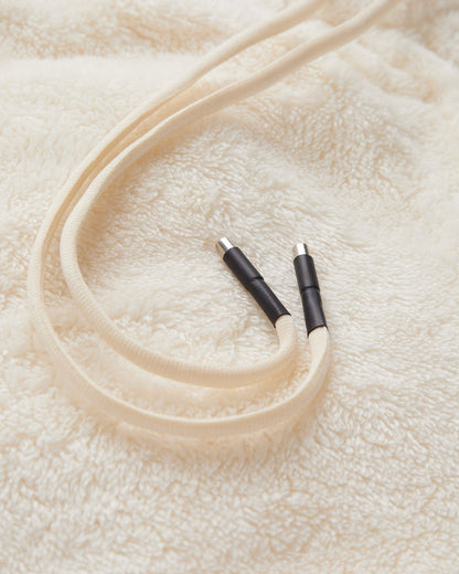 A close-up shot of the soft, fleecy fabric of The Teddy Pant in cream, highlighting the elasticated drawstring waist with its metal and black rubber tips.