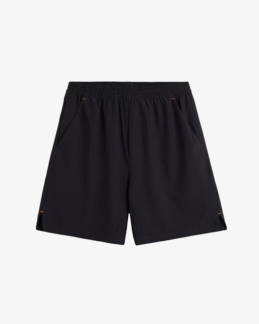 A front view of The Training Shorts in black, laid flat on a white background. The image highlights the elastic waistband, slanted side pockets, and side slits.