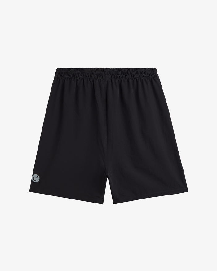 A back view of The Training Shorts in black, laid flat on a white background. The image highlights the elasticated waistband and the reflective c'est normal logo on the leg.